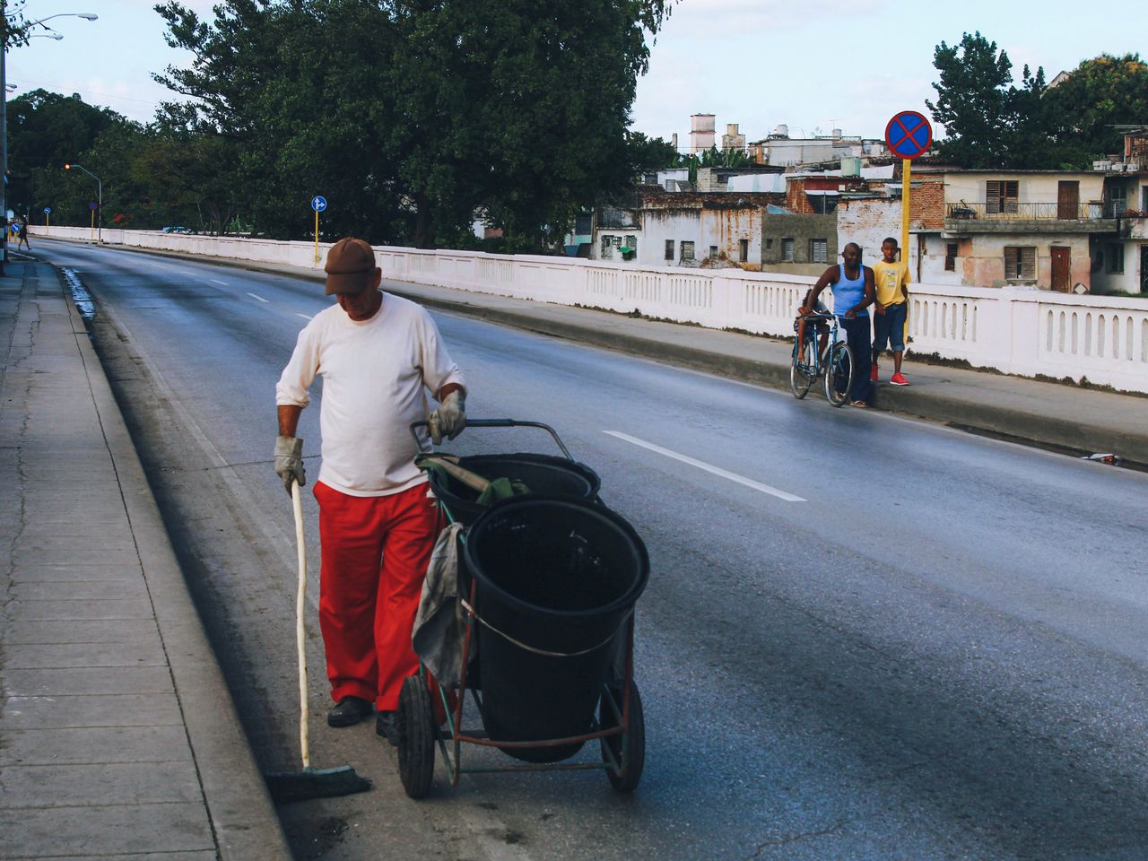 Man cleaning a city sidewalk with a pushcart, illustrating urban maintenance.